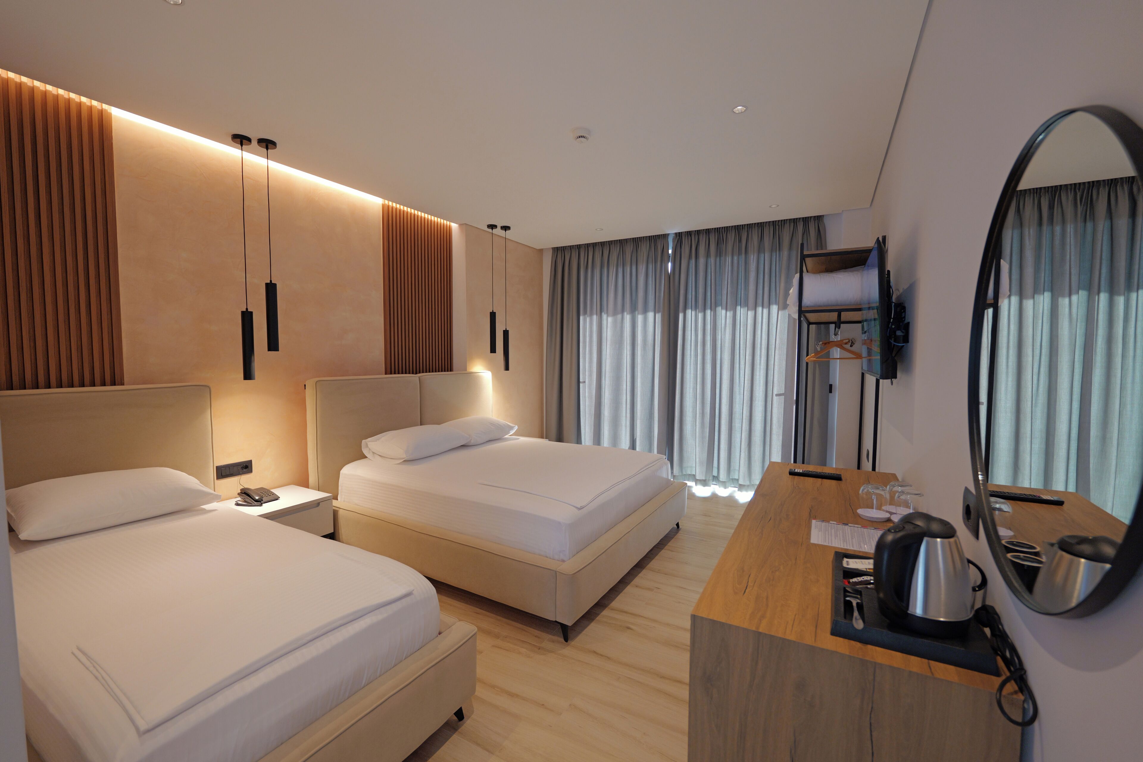 Una habitación de hotel con dos camas, un escritorio de madera, un espejo y una televisión.