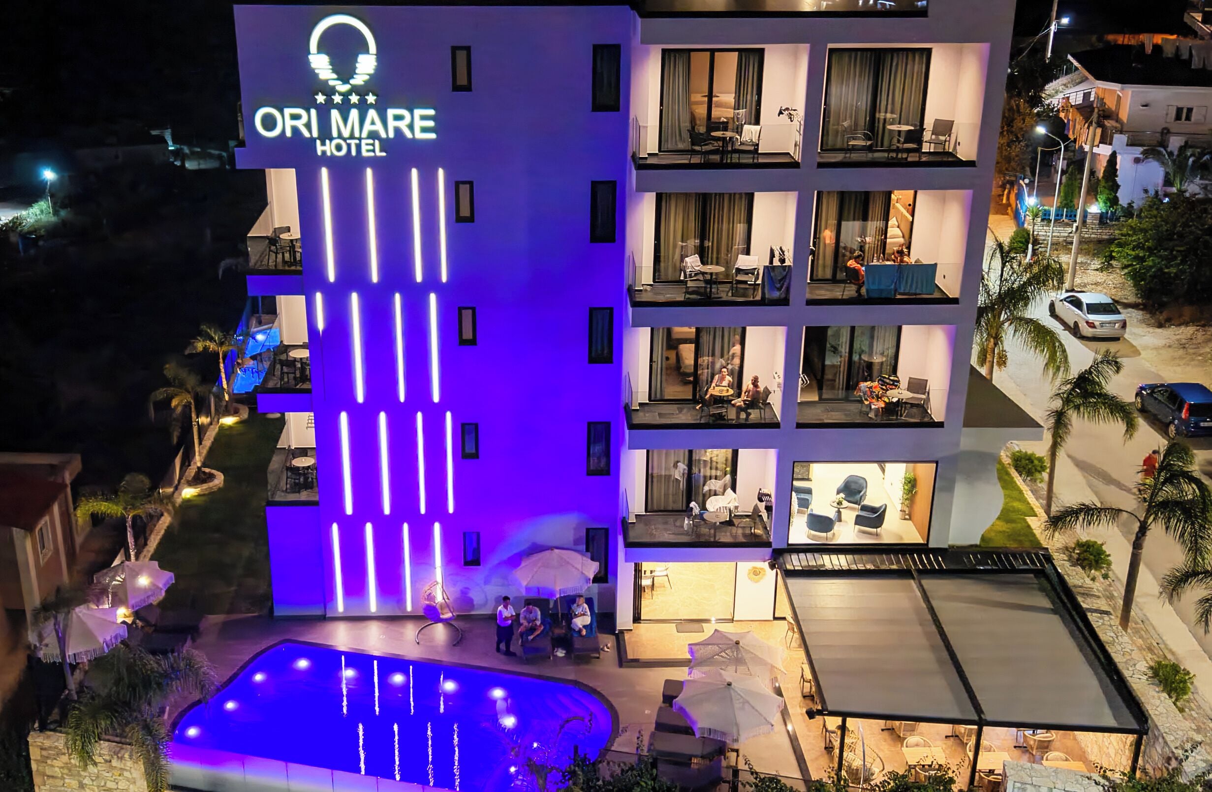 A multi-story hotel with a pool and outdoor seating.