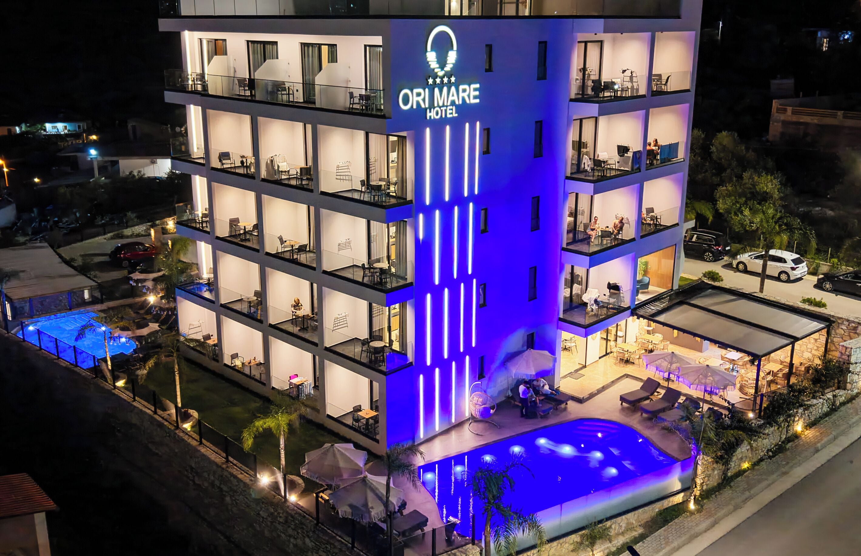 A multi-story hotel with a swimming pool, outdoor seating, and balconies.