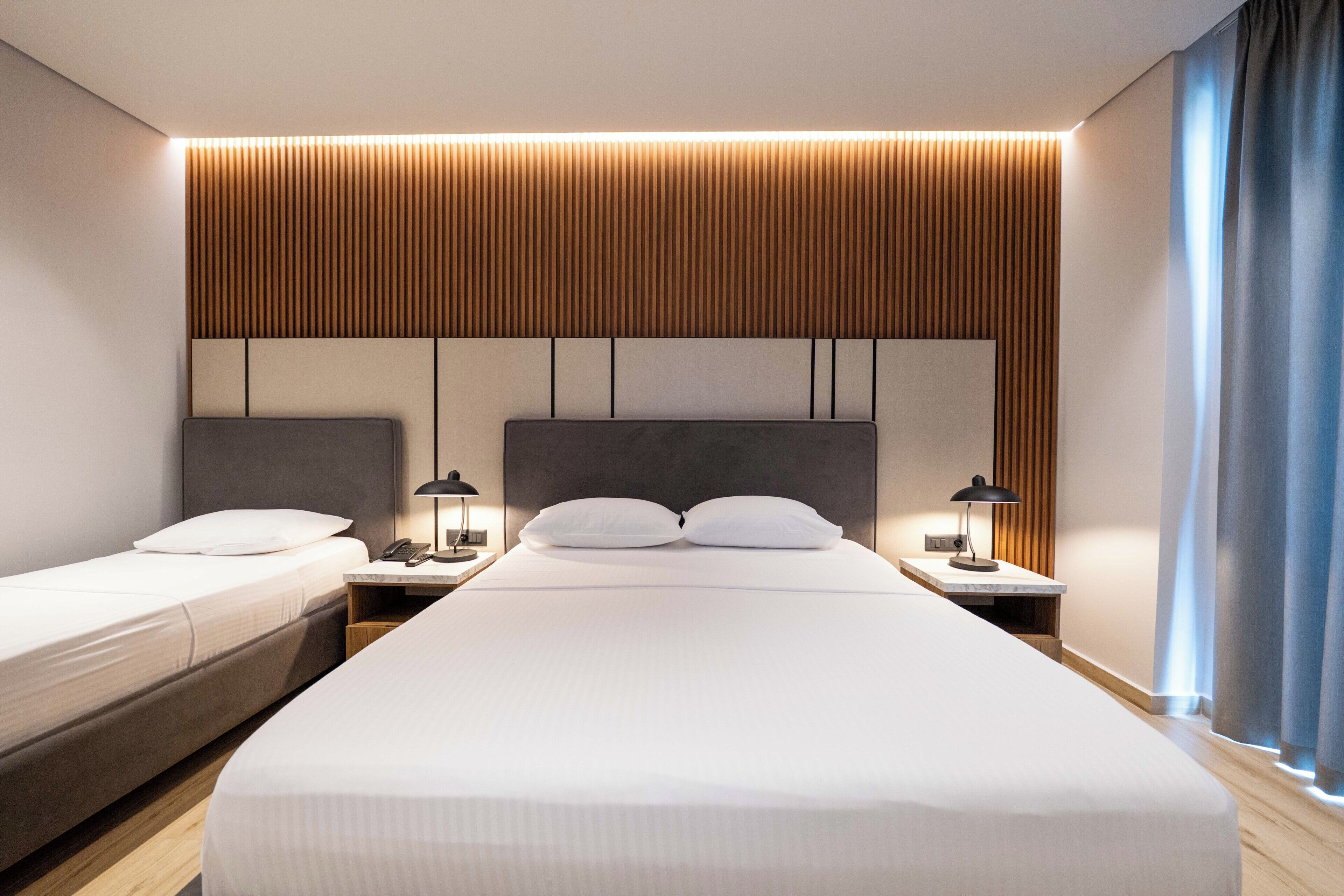 Habitación de hotel con una cama grande, dos mesitas de noche y un panel de pared de madera.