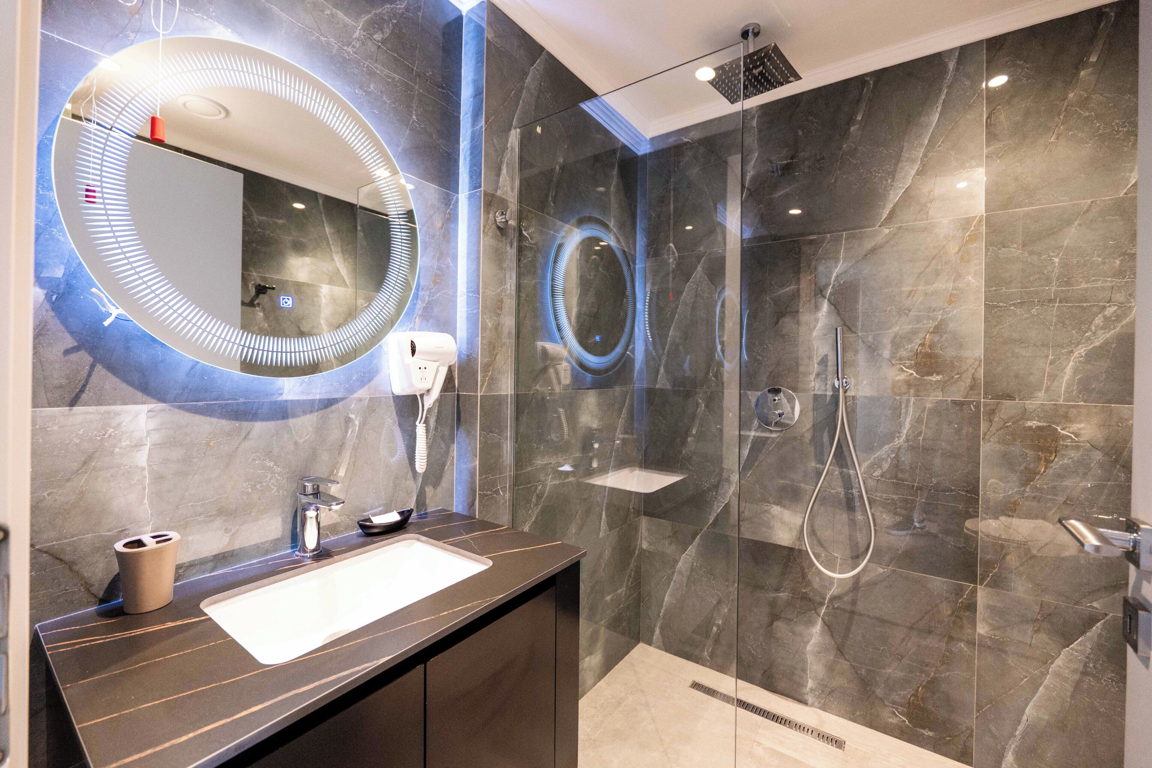 Un baño moderno con un espejo grande, un lavabo y una zona de ducha.