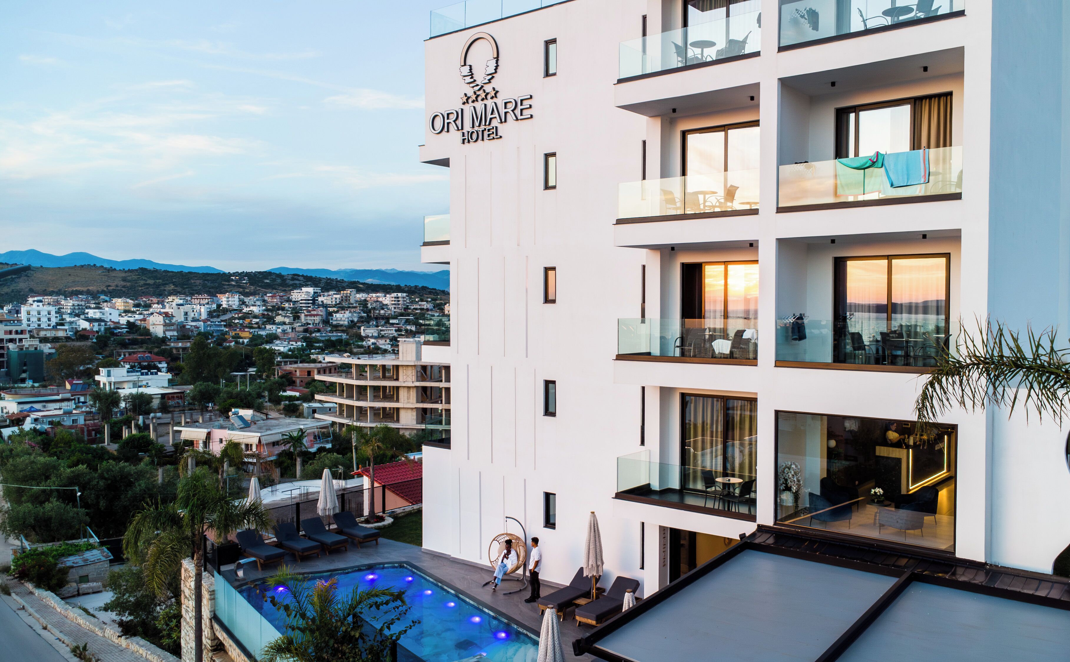 A hotel with a rooftop pool, multiple balconies, and a view of the cityscape.
