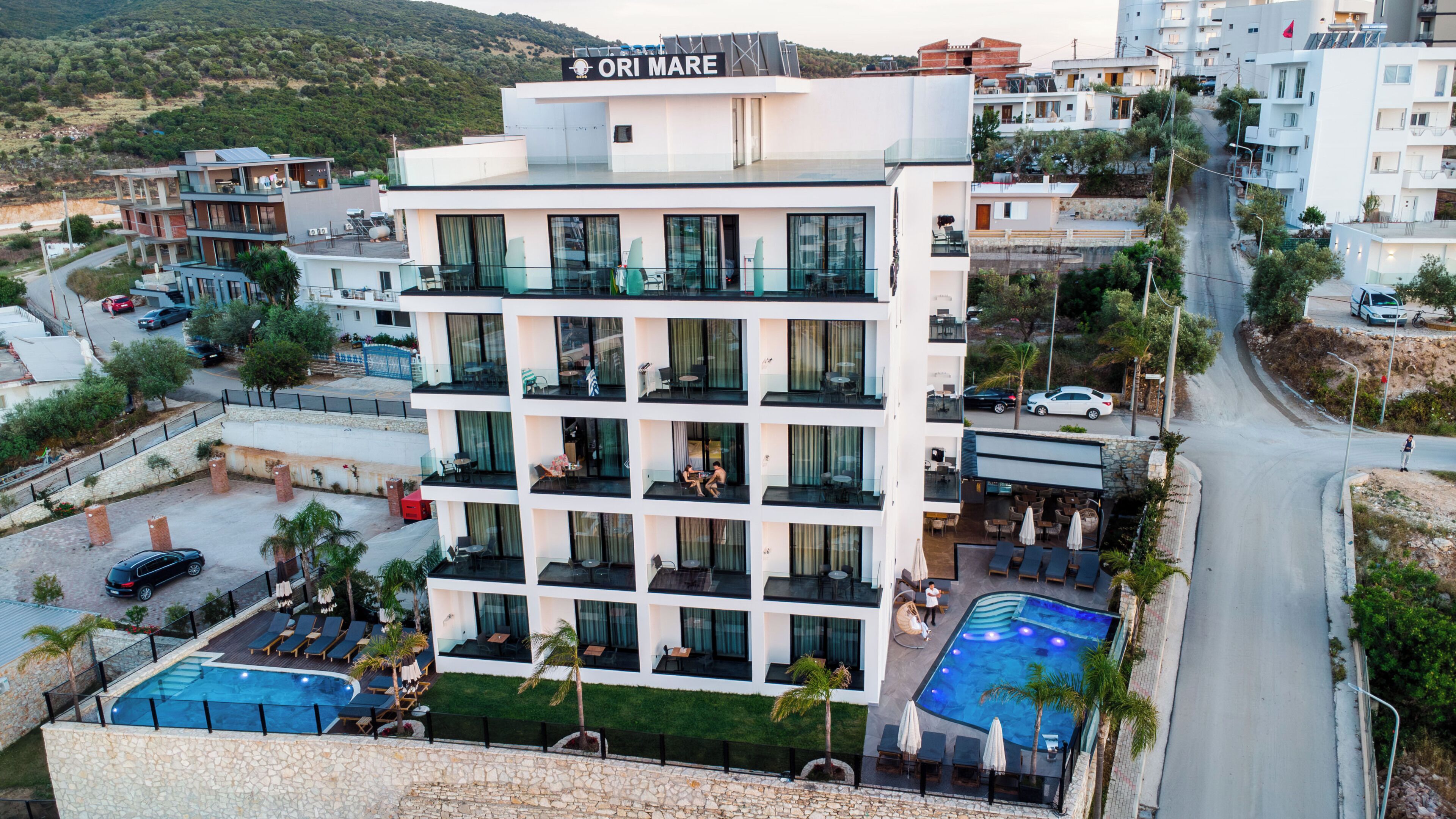 Un hotel de varios pisos con balcones, una piscina y vistas del entorno.