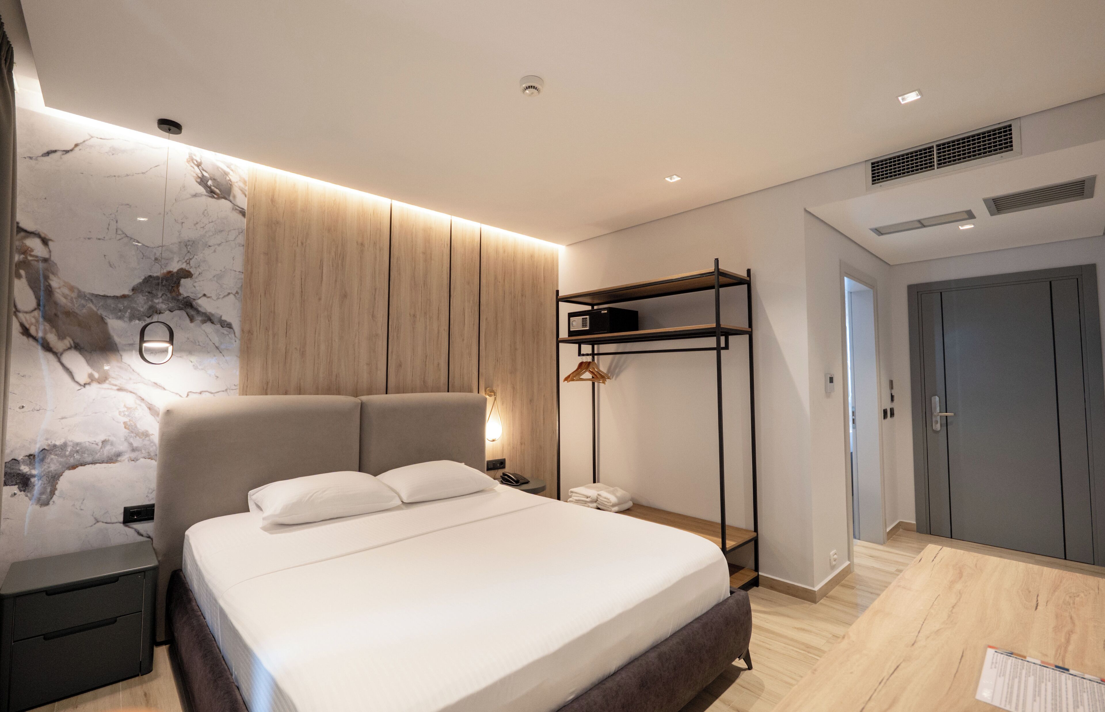 Ein modernes Schlafzimmer mit einem großen Bett, einem Nachttisch, einem Holzschrank und einer eingebauten Regaleinheit.