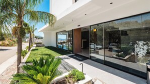 A modern building with a glass facade, a palm tree, and a well-maintained lawn. - Ori Mare Hotel (Ksamil)