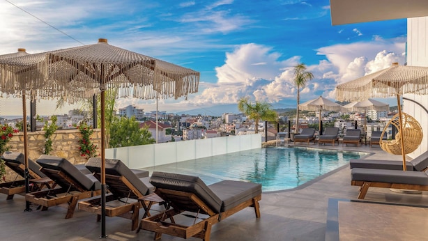 A rooftop pool area with lounge chairs and umbrellas, overlooking a cityscape. - Ori Mare Hotel (Ksamil)