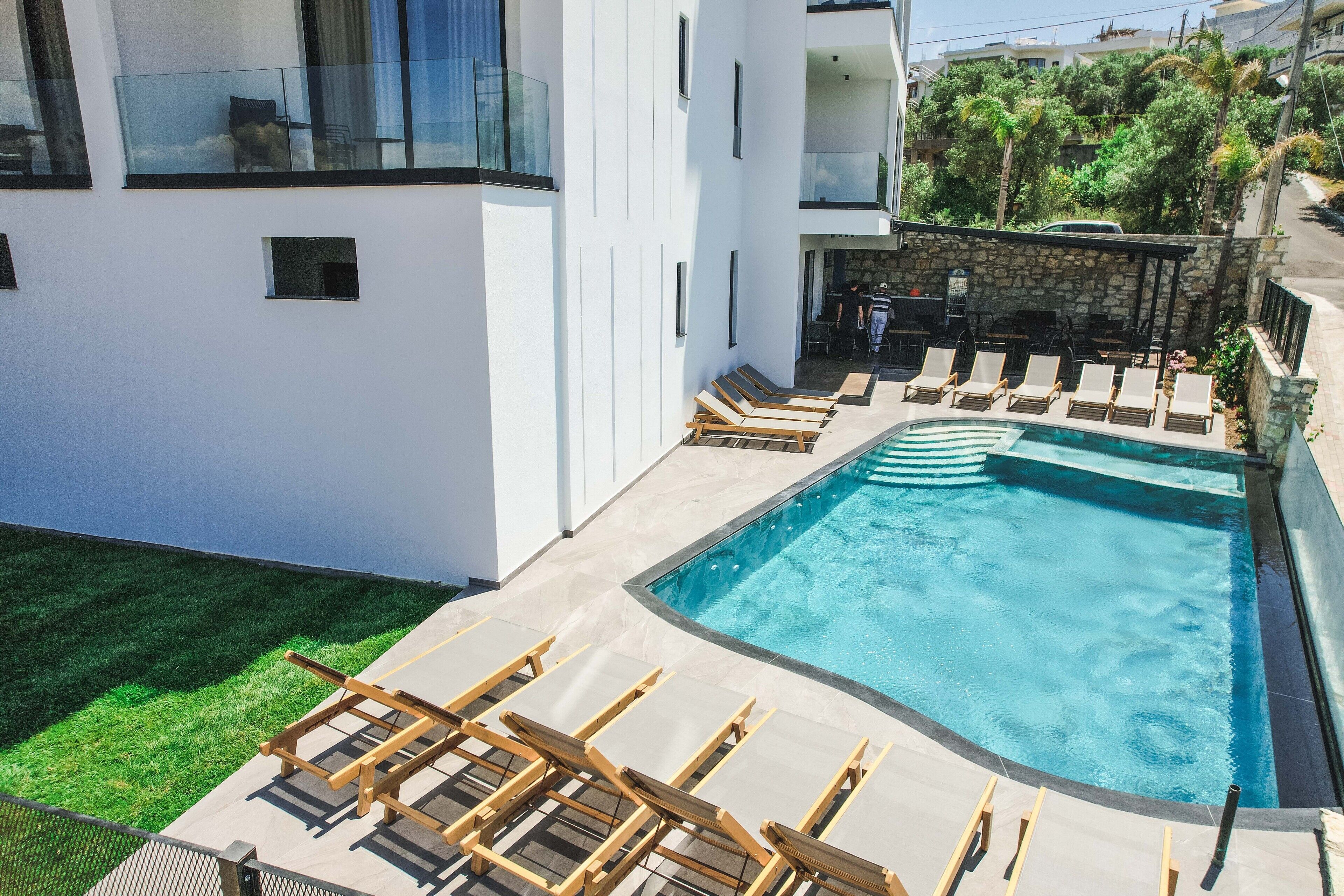Un bâtiment moderne doté d’une piscine, de chaises longues et d’un mur en pierre.