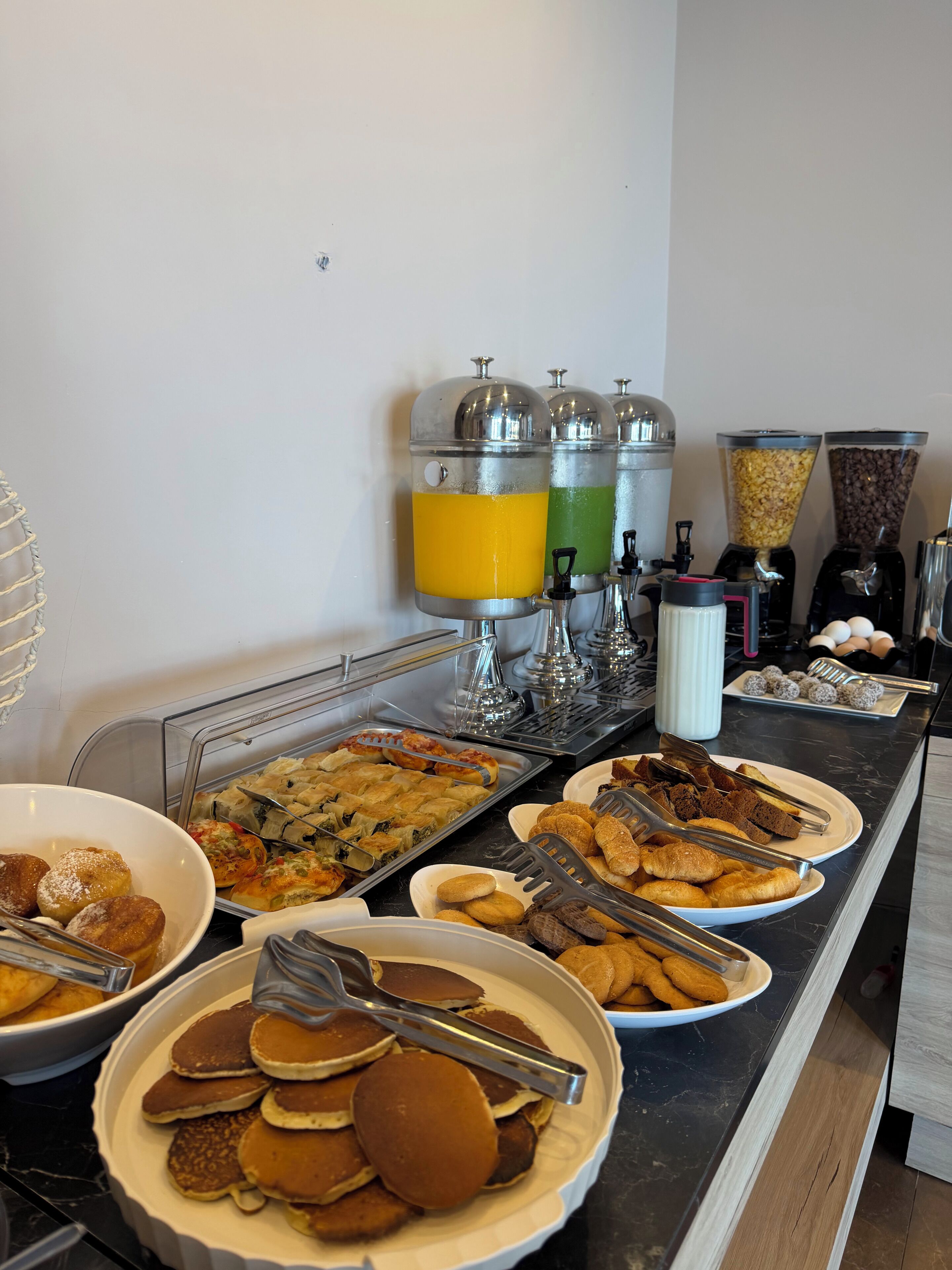 A buffet with various food items, including pancakes, pastries, and a coffee station.