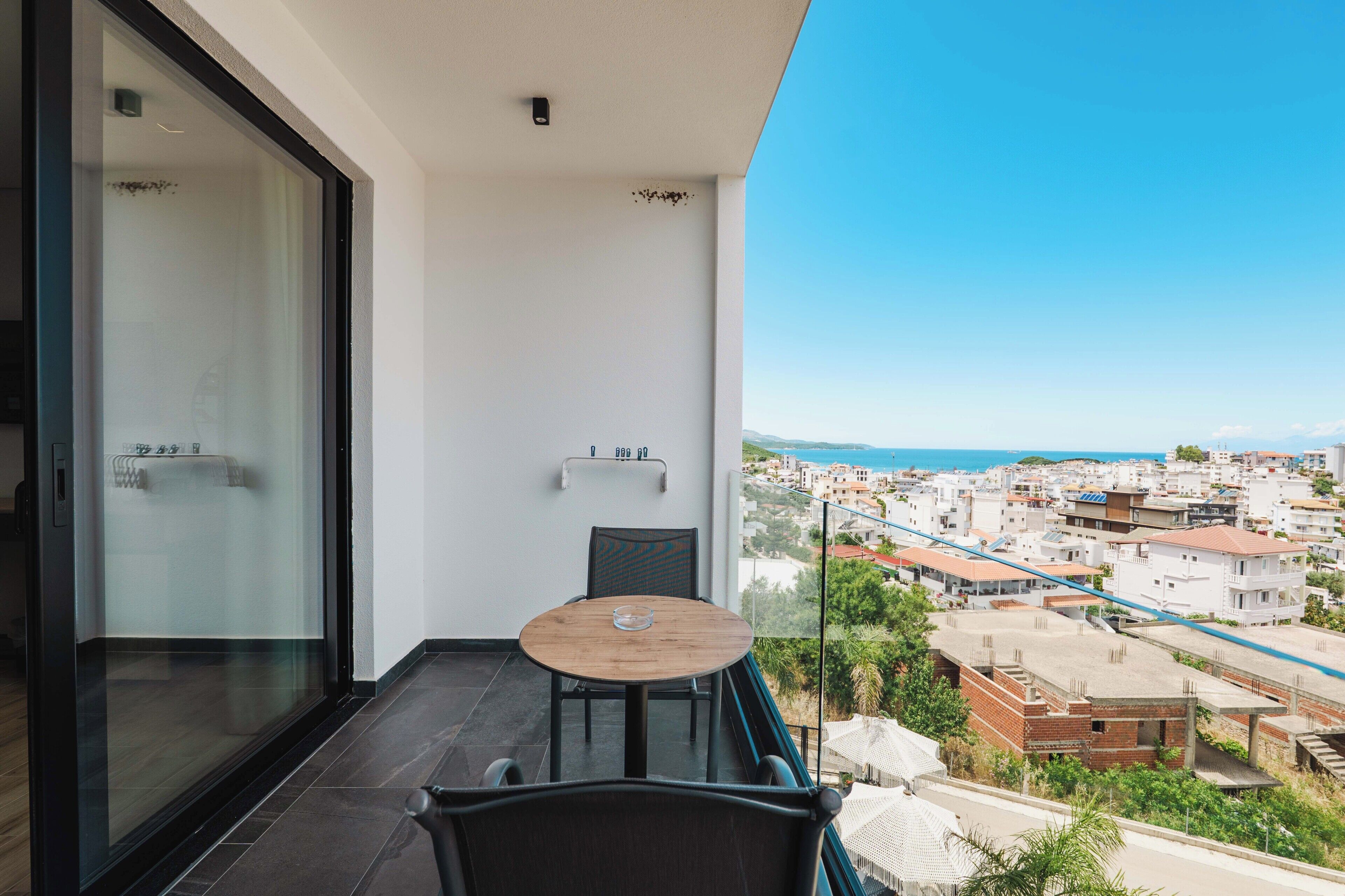 A balcony with a table and chairs, a glass door, and a city view.