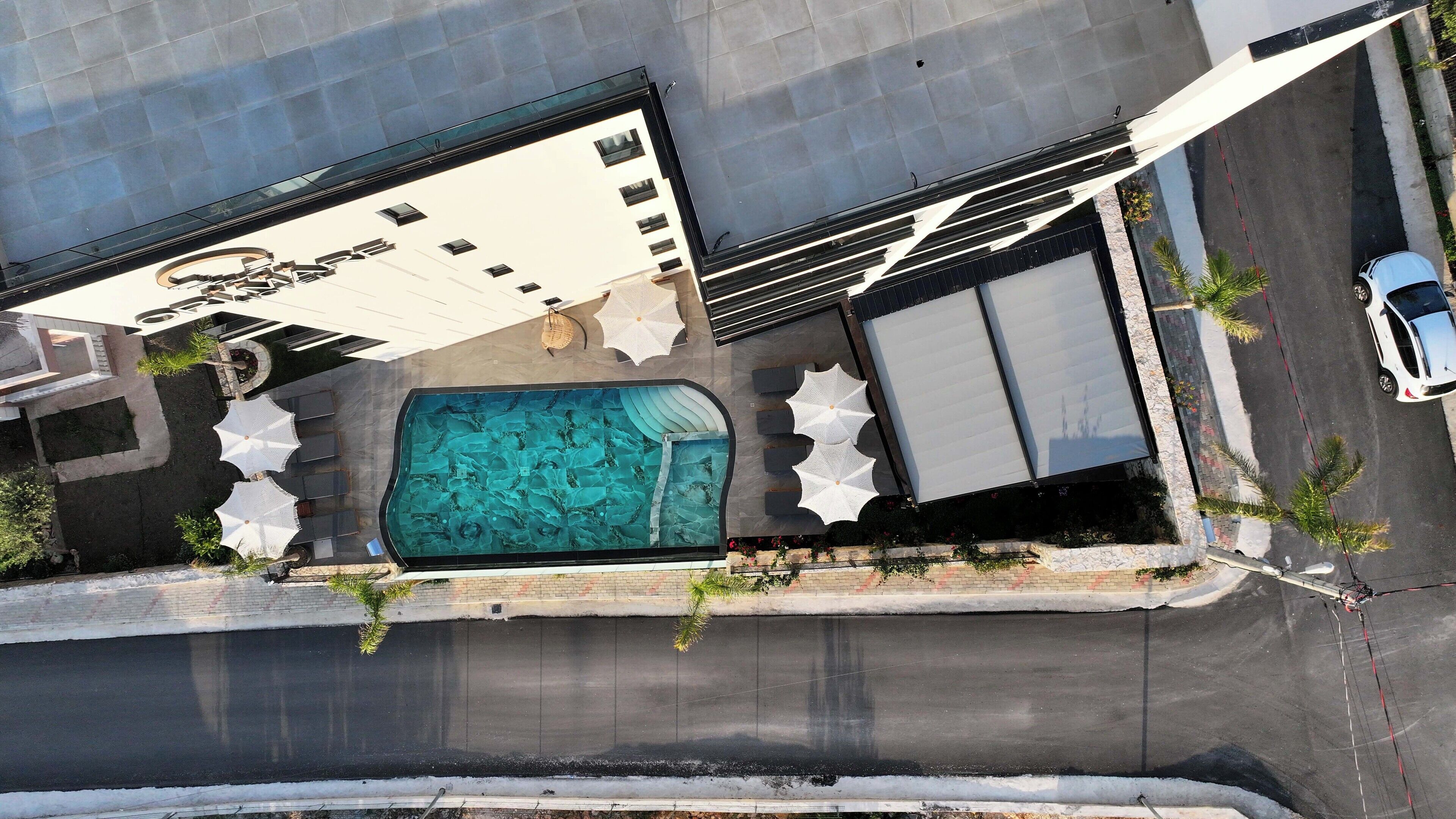 An aerial view of a hotel with a swimming pool, outdoor seating, and a covered area.