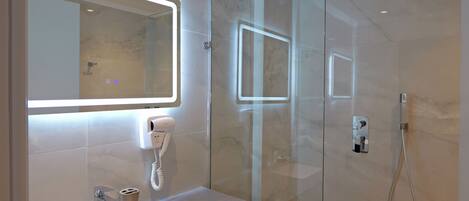 A modern bathroom with a glass shower enclosure, a built-in sink, and a mirror with integrated lighting.