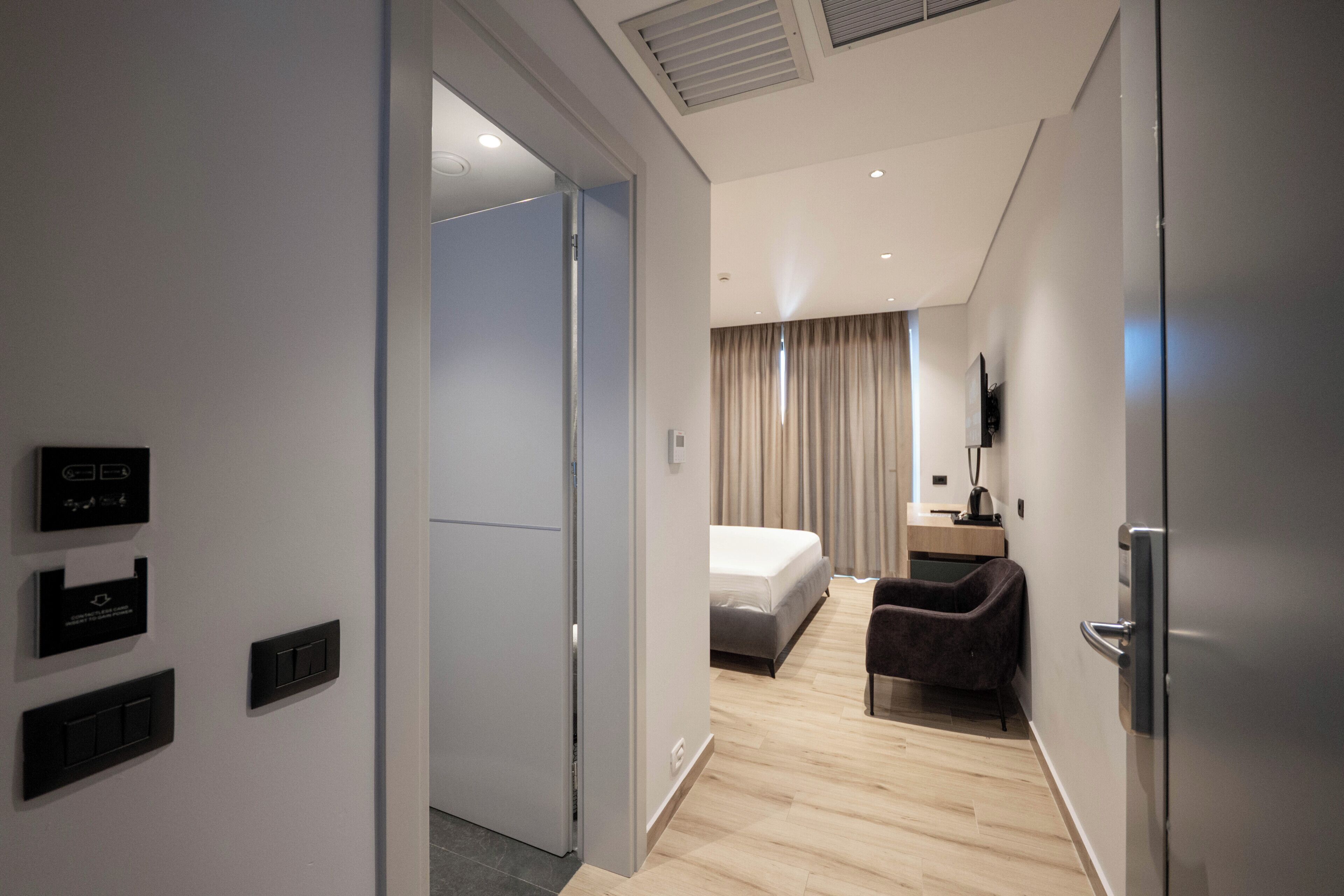 Una habitación de hotel moderna con cama, escritorio, silla y televisor.