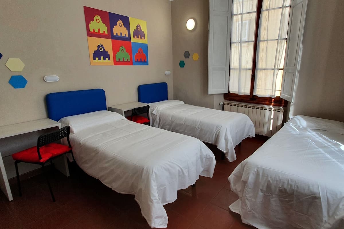 A room with two single beds, a desk, and a chair.