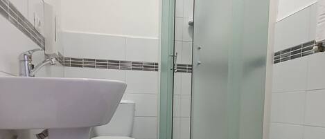 A bathroom with a white sink, toilet, and shower.