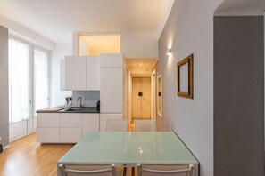 A modern kitchen with white cabinets, a glass table, and a wooden floor. - Sant'Ambrogio - Milan, central apartament for 5 (Milano)