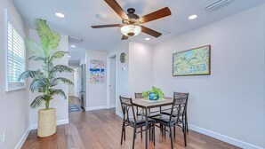 A dining area with a ceiling fan, wooden flooring, and a table with chairs.