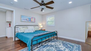 A bedroom with a bed, a ceiling fan, a window, and a door.