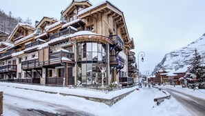 A traditional wooden building with balconies, large windows, and a snow-covered landscape. - Luxury Apartment with Private Jacuzzi and Stunning Views (Val-d'Isère)