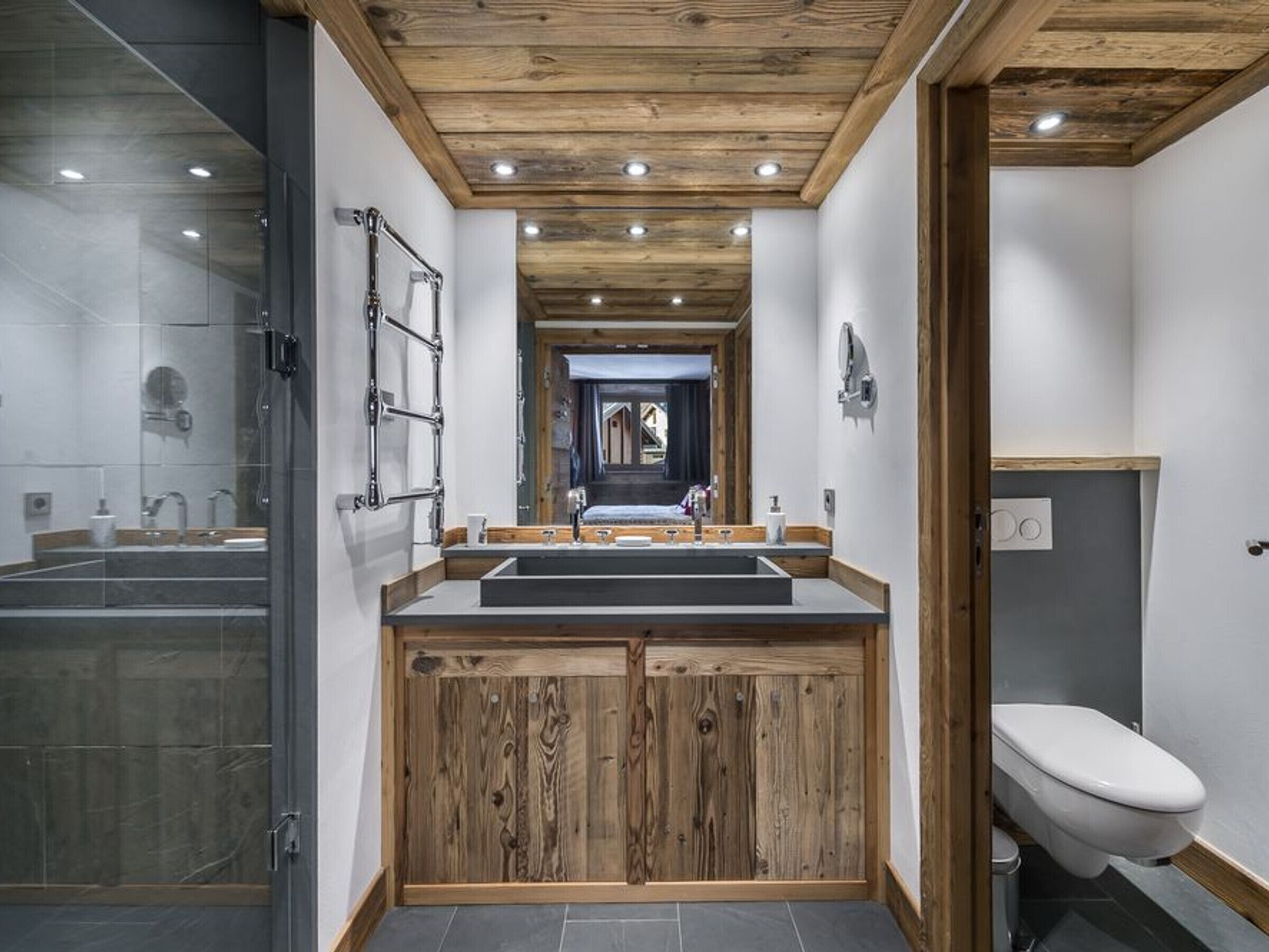 A modern bathroom with a wooden vanity, a glass shower enclosure, and a white toilet.
