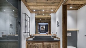 A modern bathroom with a wooden vanity, a glass shower enclosure, and a white toilet. - Luxury Apartment with Private Jacuzzi and Stunning Views (Val-d'Isère)
