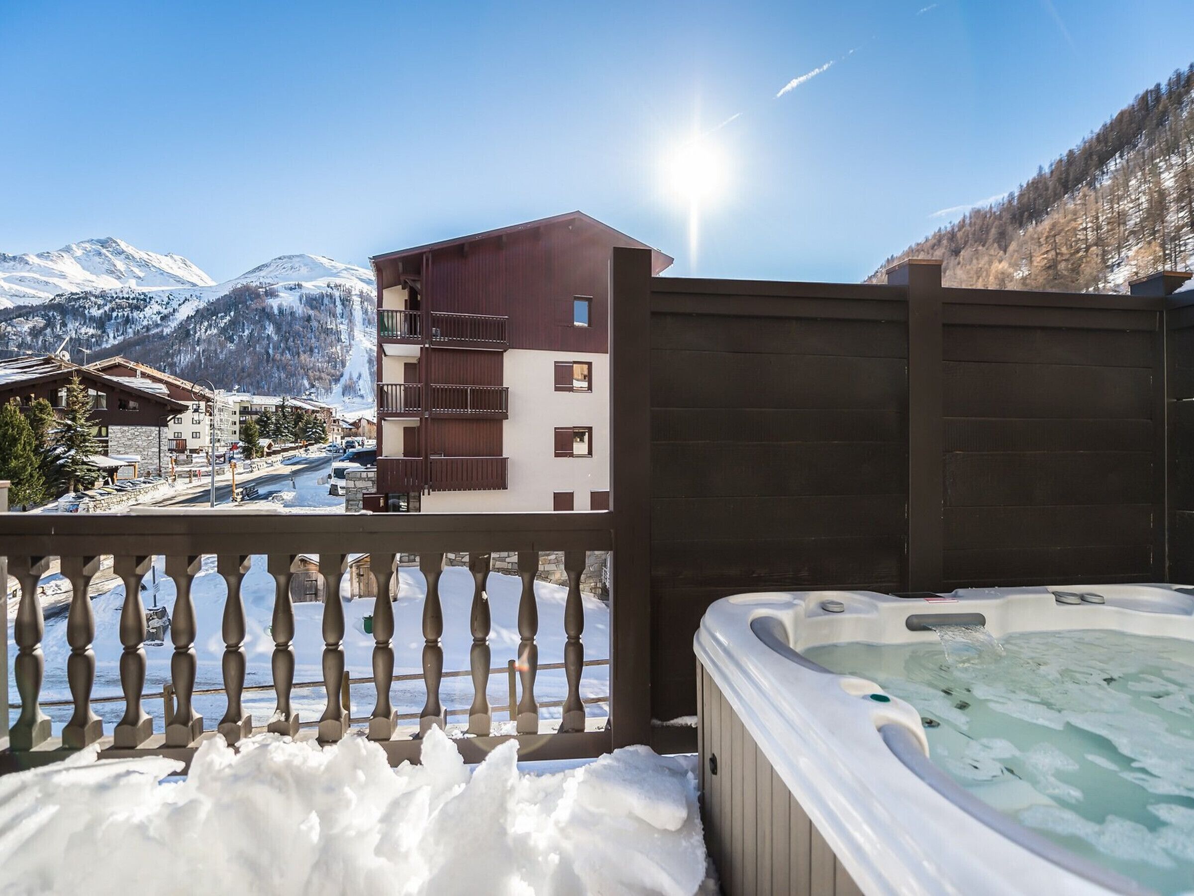 Ein Whirlpool auf einem Balkon mit Blick auf einen Berg und ein Gebäude.