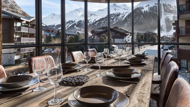 A dining table set for six with a mountain view, wooden table, and leather chairs. - Luxury Apartment with Private Jacuzzi and Stunning Views (Val-d'Isère)