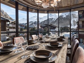 Une table à manger dressée pour six personnes, avec vue sur les montagnes, une table en bois et des chaises en cuir.