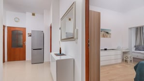 A modern kitchen with a refrigerator, a built-in oven, a sink, and a dining area with a table and chairs.