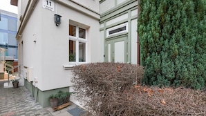 A building with a number '11' sign, a green door, and a potted plant near the entrance.