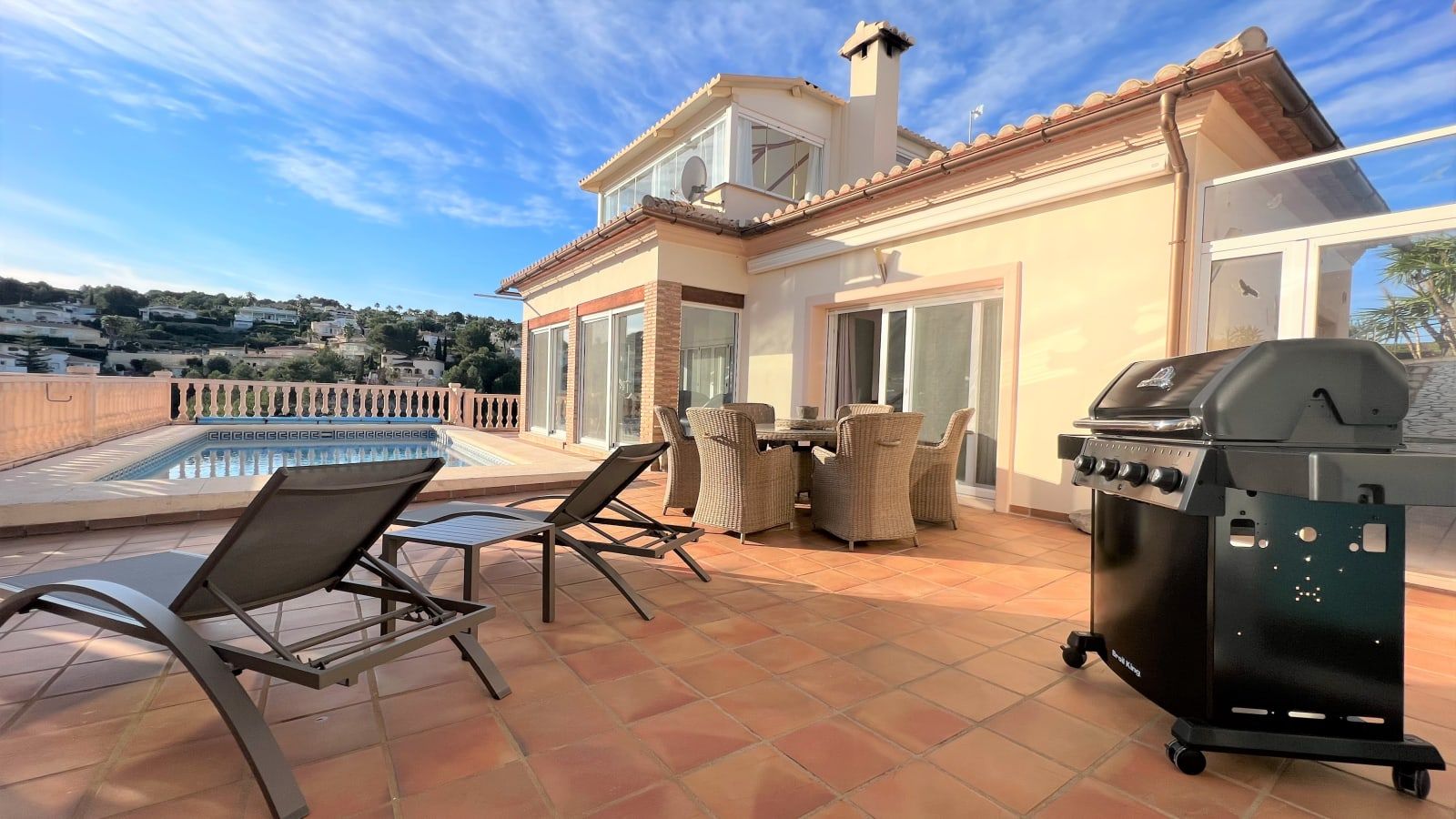Un pati amb una piscina, mobles d'exterior i una barbacoa.