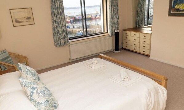 Une chambre à coucher avec un lit, une commode, une fenêtre donnant sur un beau paysage et un radiateur.