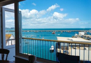 Un balcón con vista a un puerto, barcos y cielo despejado.