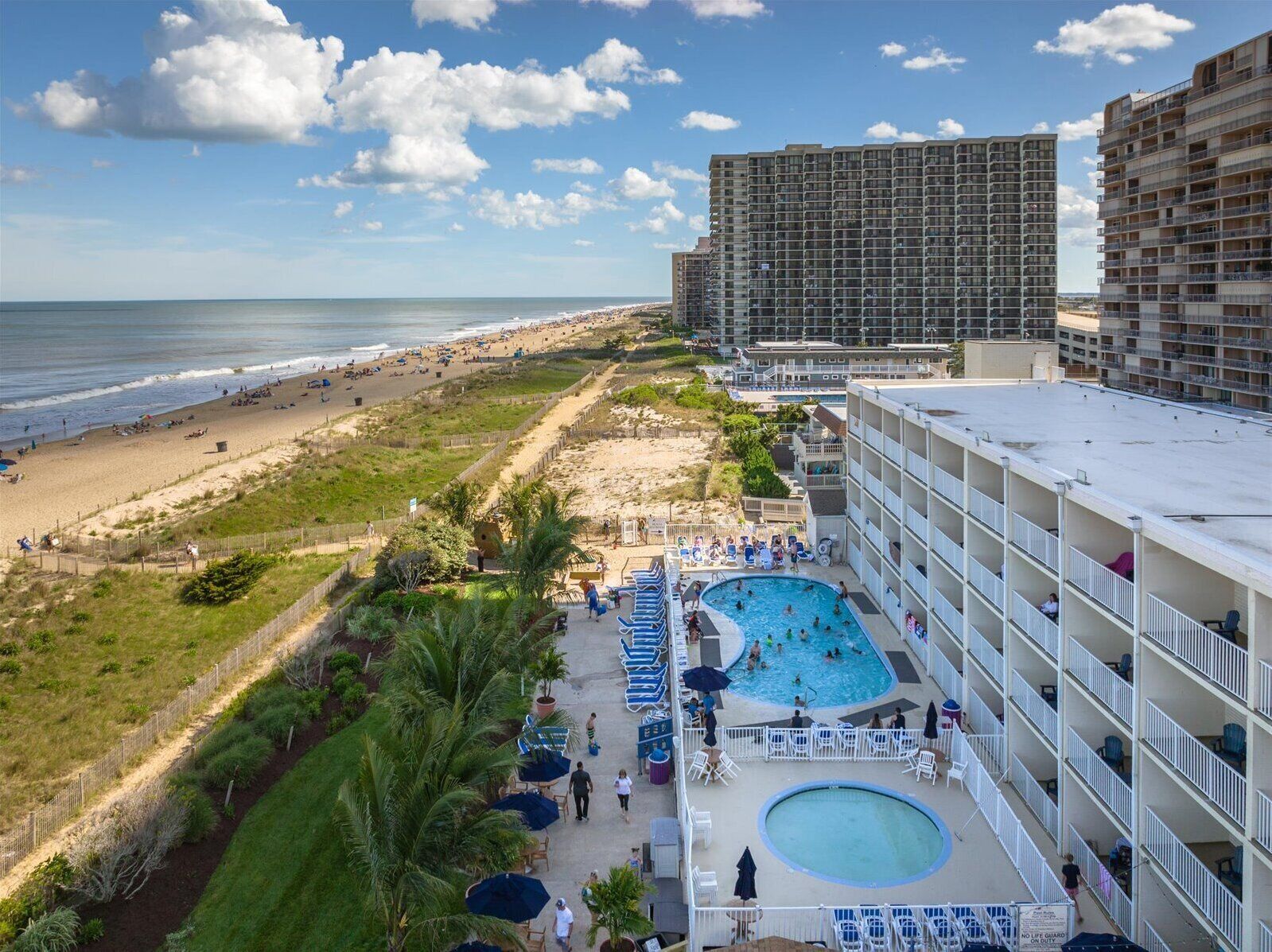 A hotel with a rooftop pool, beach view, and multiple balconies.
