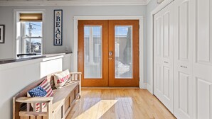 A hallway with a wooden bench, a double door with frosted glass panels, and a sign above the door that reads "BEACH HOUSE". - Beachside Retreat on the Hill (Old Orchard Beach)