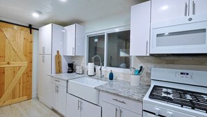 A modern kitchen with white cabinets, a granite countertop, a stainless steel stove, and a wooden door. - Vacation home ,silver springs, salt spring ,Ocala world equestrian center.  (Ocala)
