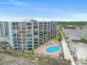 A multi-story hotel with a pool area, outdoor seating, and a view of the surrounding landscape.