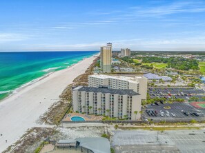 A coastal hotel with a pool, beach access, and a parking lot.
