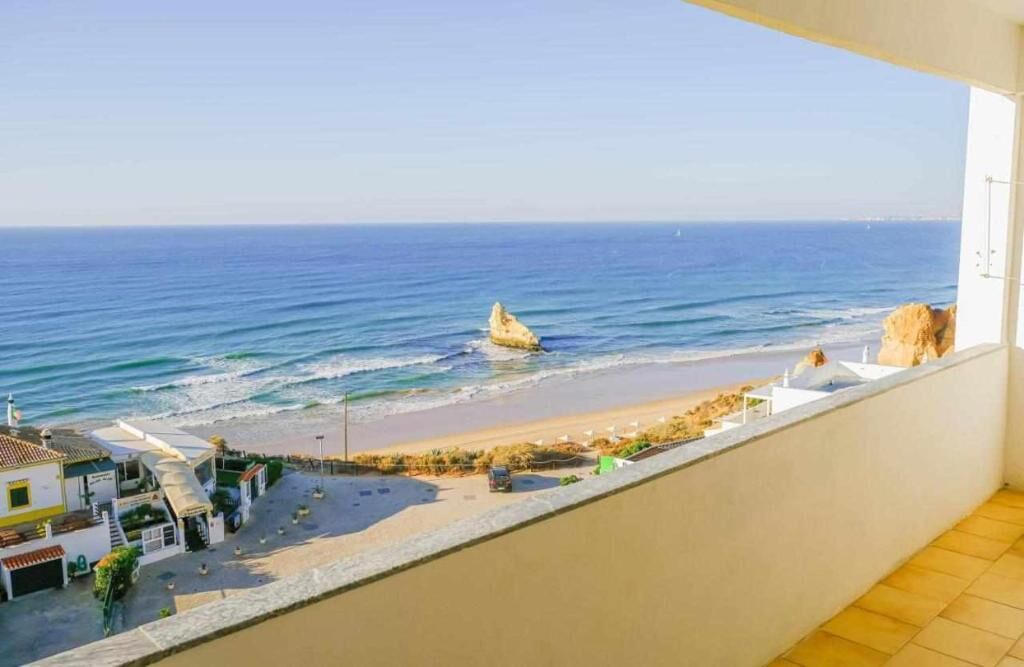 A balcony with a view of the beach and ocean.