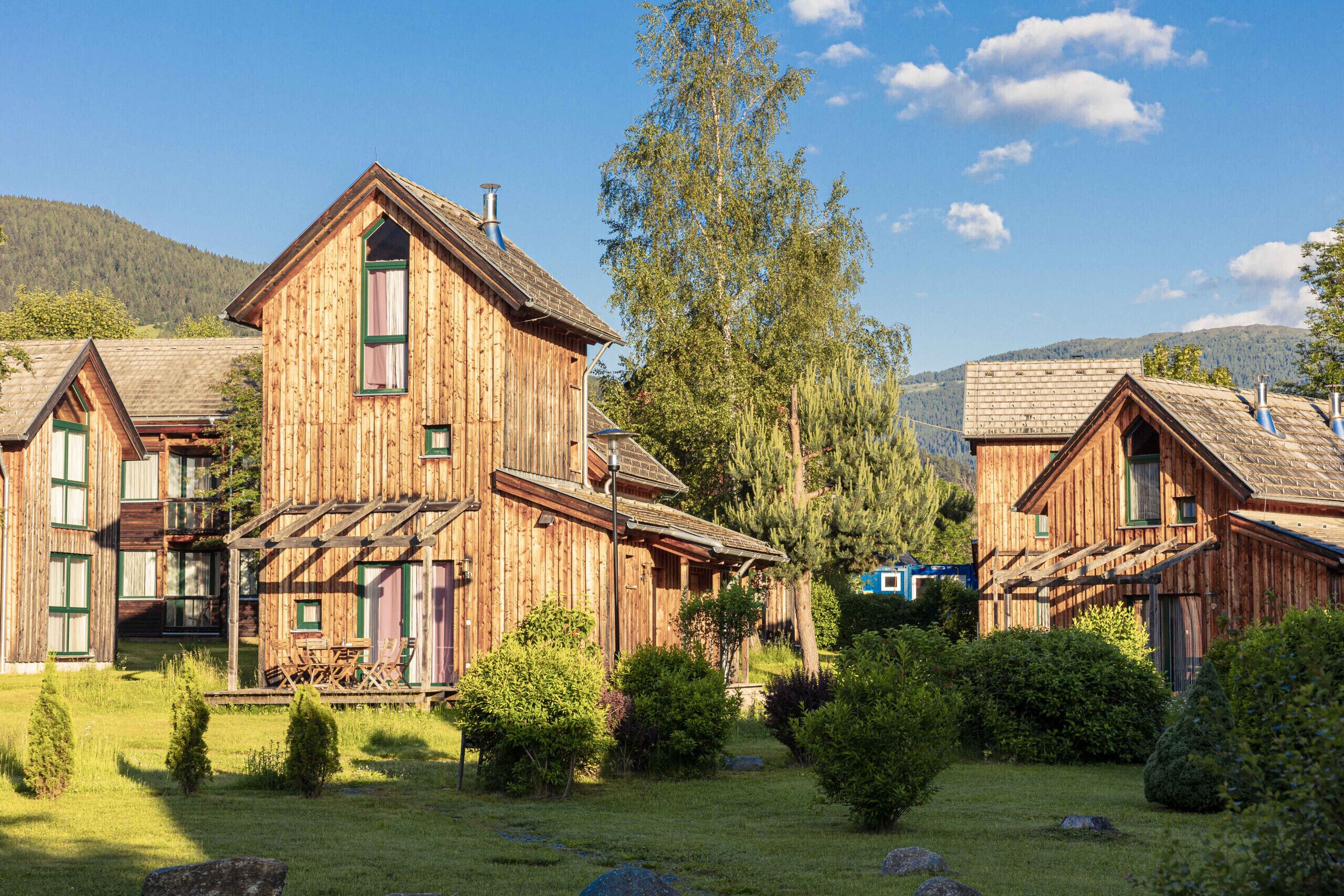 A rustic wooden building with a balcony and a small garden area.