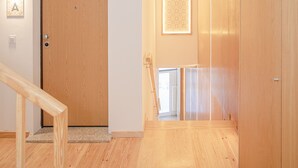 A hallway with wooden flooring, a wooden door, and a framed picture on the wall. - Liiiving-Mouzinho Residence Apartment 1F (Porto)