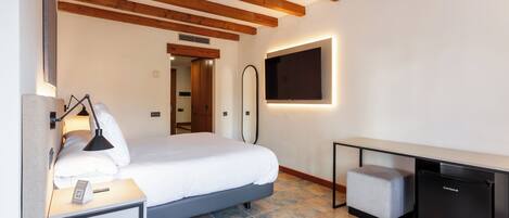 A modern hotel room with a bed, bedside table, lamp, and a small black refrigerator.