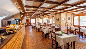Un restaurant avec des poutres en bois, des murs en briques et un sol carrelé. Les tables sont dressées avec des nappes blanches et des chaises.
