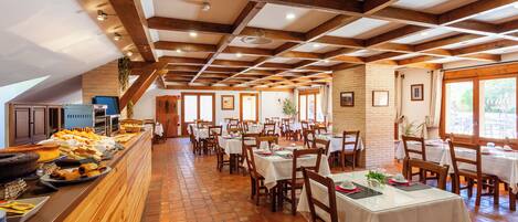 A restaurant with wooden beams, brick walls, and a tiled floor. Tables are set with white tablecloths and chairs.