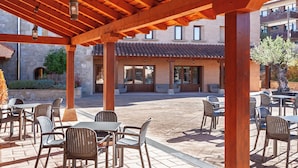 An outdoor patio with wooden pergola, tables, and chairs.