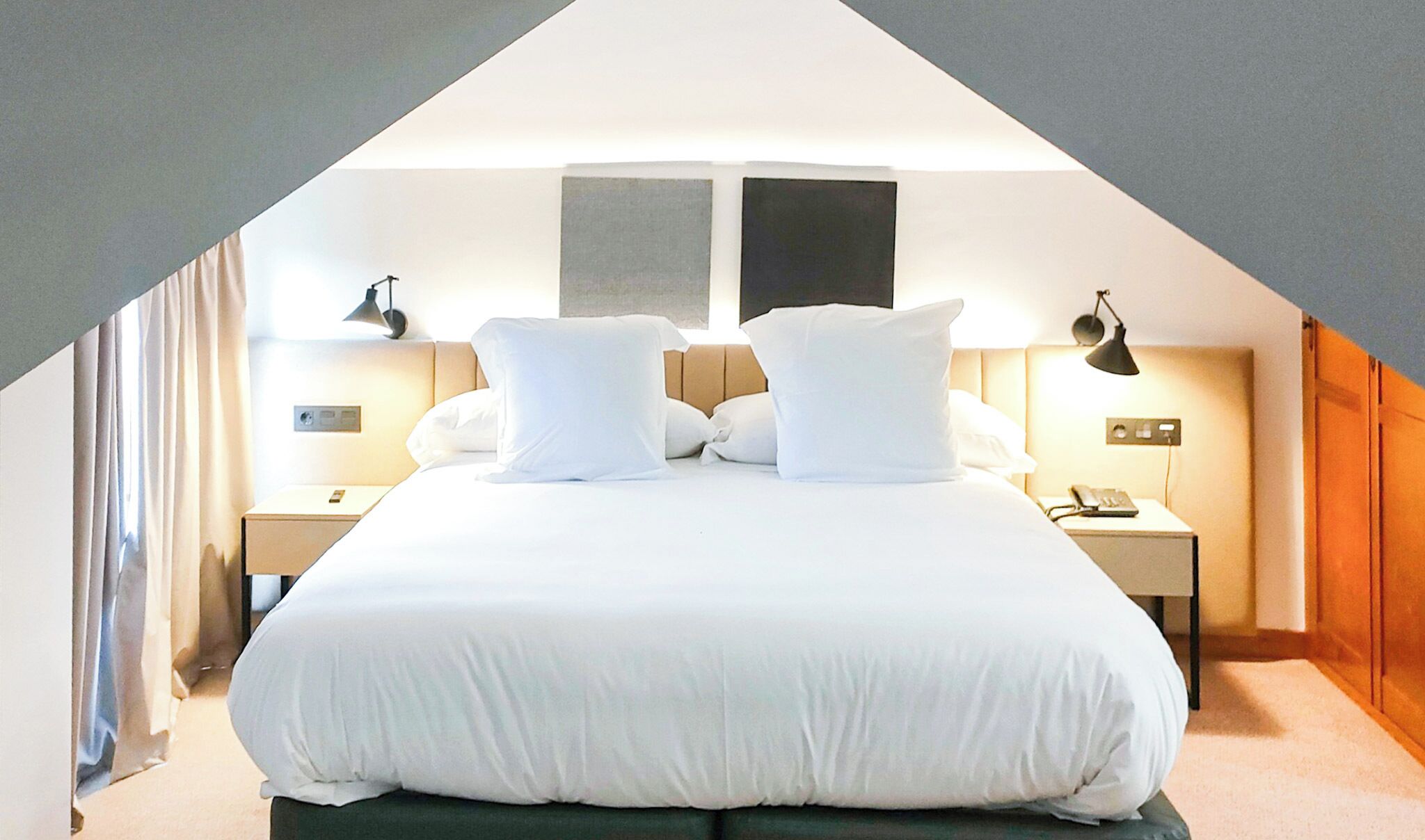 Een hotelkamer met een groot bed, twee nachtkastjes, een lamp en uitzicht op de lucht.