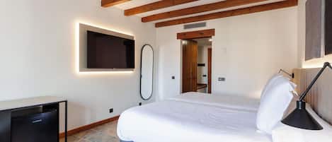 Een slaapkamer met een bed, een bedlampje en een klein bureau met een koelkast.
