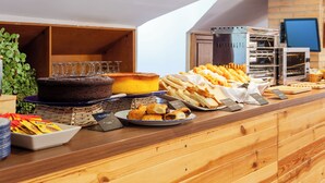 A buffet counter with various food items, including a cake, pastries, and bread.