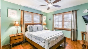 A bedroom with a bed, two bedside tables with lamps, a ceiling fan, and a TV on a stand.