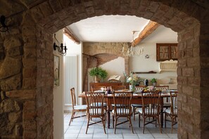 A rustic dining area with a stone archway, wooden furniture, and a chandelier. - Villa Sunshine (Gambassi Terme)