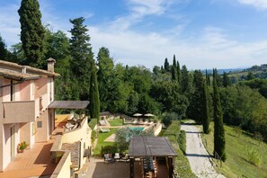 A villa with a swimming pool, outdoor seating, and a view of the surrounding forest. - Villa Sunshine (Gambassi Terme)
